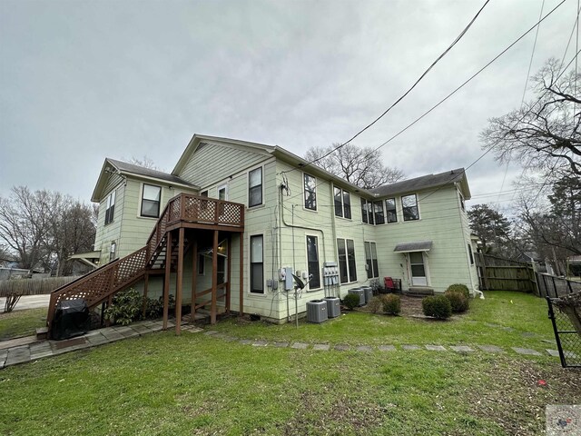 rear view of property with a deck, central air condition unit, and a yard