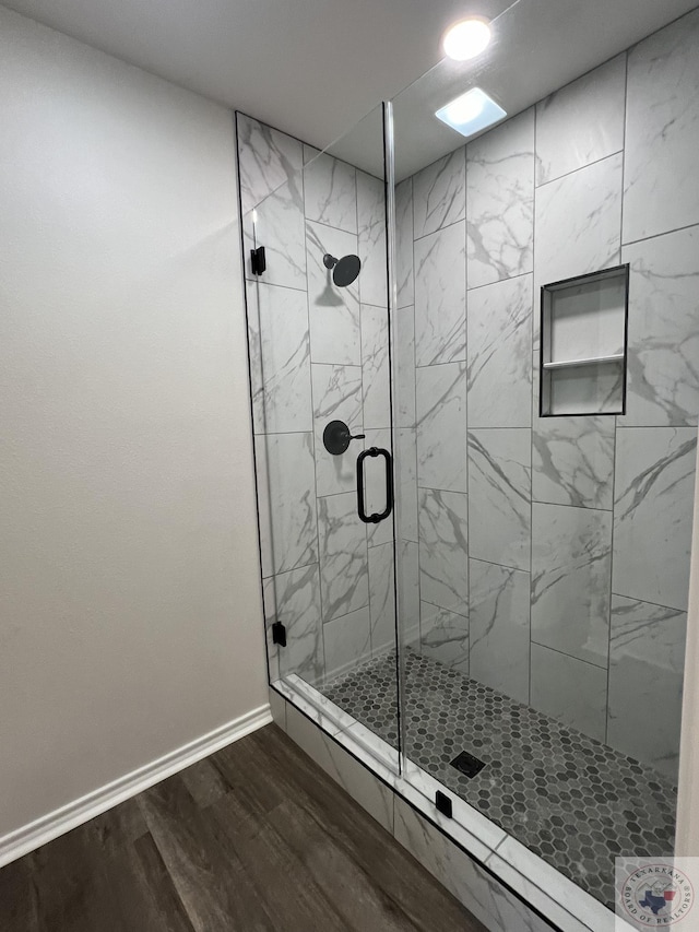 bathroom with a stall shower, baseboards, and wood finished floors