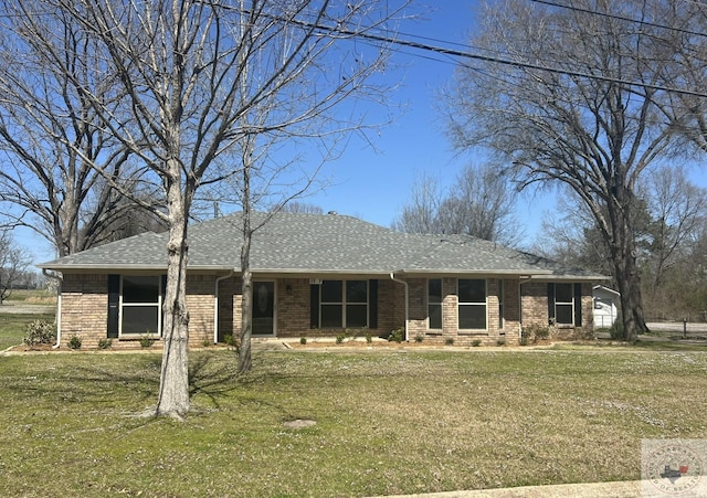 view of front of home with brick siding, a garage, a front yard, and roof with shingles