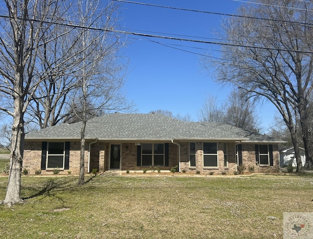 view of front of house featuring brick siding, roof with shingles, and a front yard