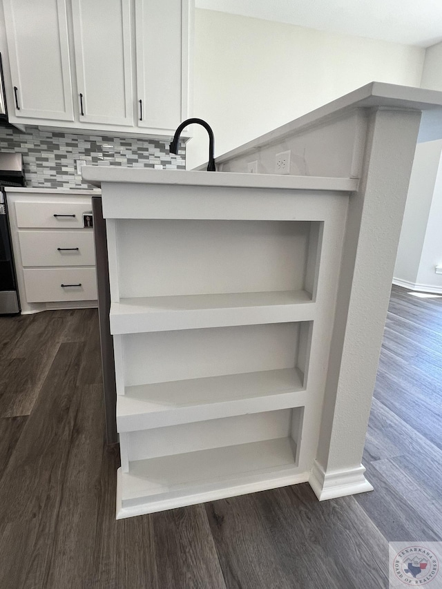 interior details featuring open shelves, a sink, stainless steel range, light countertops, and dark wood-type flooring