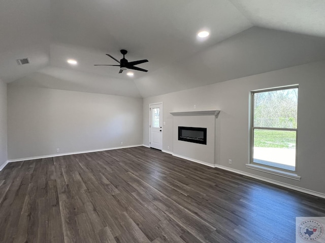 unfurnished living room with dark wood-style floors, visible vents, baseboards, vaulted ceiling, and a glass covered fireplace