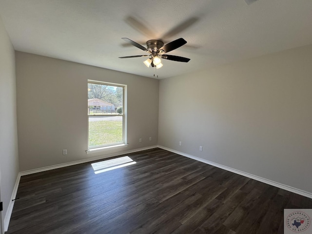 unfurnished room with a ceiling fan, dark wood-type flooring, and baseboards