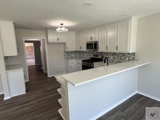 kitchen featuring dark wood-type flooring, appliances with stainless steel finishes, a peninsula, and light countertops