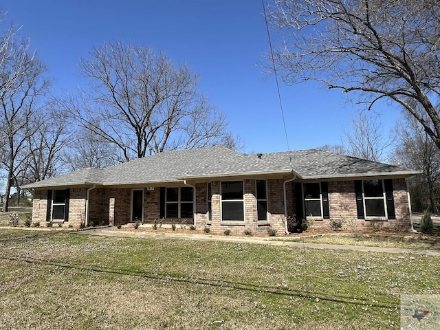 view of front of property featuring brick siding, a shingled roof, and a front yard