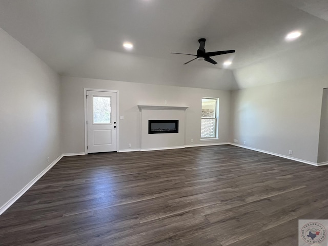 unfurnished living room with plenty of natural light, a fireplace, dark wood-style flooring, and vaulted ceiling