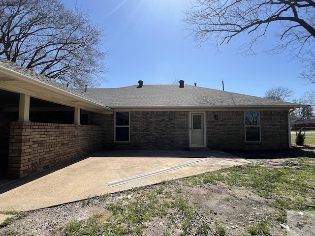 rear view of property with a patio, brick siding, and roof with shingles