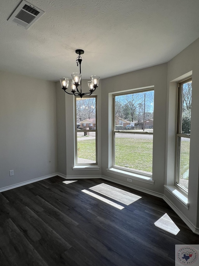 unfurnished dining area with visible vents, a notable chandelier, a healthy amount of sunlight, and dark wood-style flooring