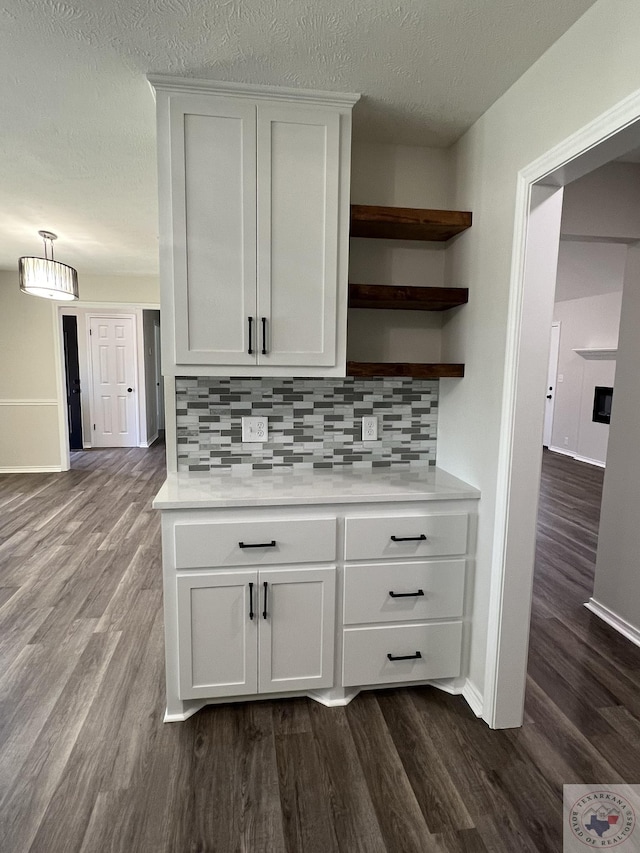 interior space with baseboards, decorative backsplash, a fireplace, dark wood-style floors, and a textured ceiling