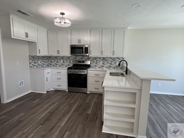 kitchen featuring visible vents, a sink, open shelves, stainless steel appliances, and a peninsula