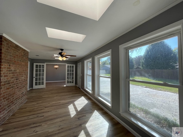 unfurnished sunroom with ceiling fan, a skylight, and a healthy amount of sunlight