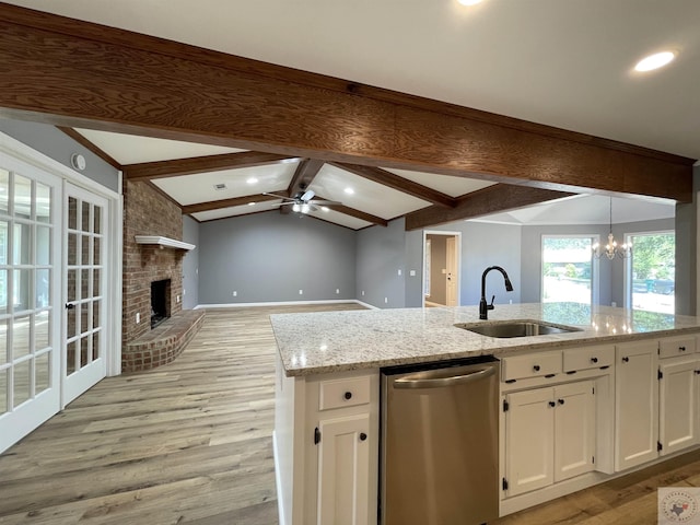 kitchen with dishwasher, sink, white cabinets, lofted ceiling with beams, and a fireplace