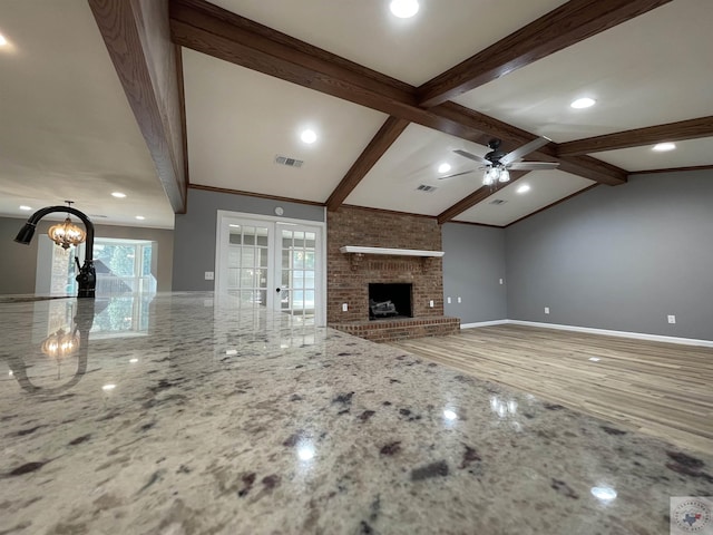 unfurnished living room with ceiling fan, a wealth of natural light, french doors, and a fireplace