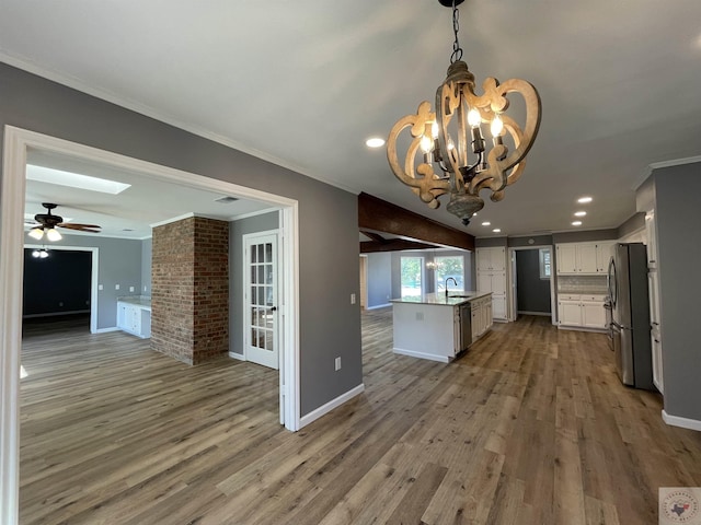 kitchen featuring pendant lighting, appliances with stainless steel finishes, sink, white cabinetry, and ornamental molding