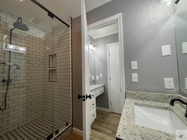 bathroom featuring hardwood / wood-style flooring, walk in shower, ornamental molding, and vanity