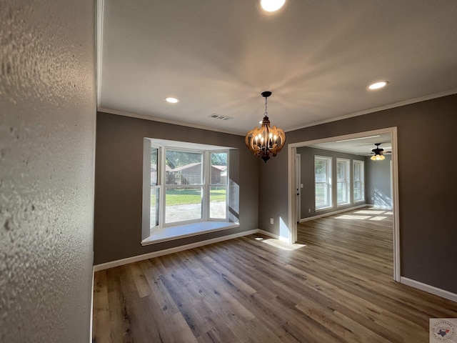 unfurnished dining area featuring hardwood / wood-style floors, crown molding, an inviting chandelier, and a healthy amount of sunlight