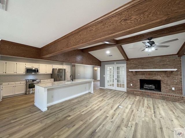 kitchen with appliances with stainless steel finishes, sink, backsplash, a kitchen island with sink, and a kitchen bar