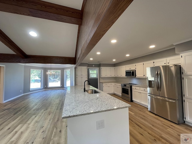 kitchen featuring appliances with stainless steel finishes, white cabinetry, sink, a kitchen island with sink, and beam ceiling