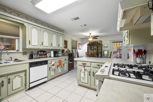 kitchen with sink, dishwasher, kitchen peninsula, and green cabinetry