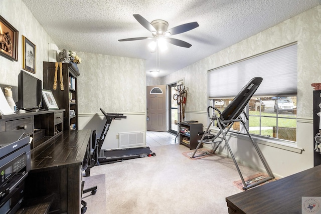 interior space with a textured ceiling, light colored carpet, and ceiling fan