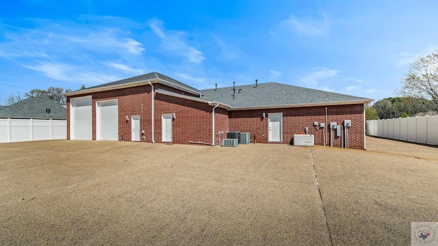 7207 N Richland Dr, Texarkana, TX 75503 - rear view of house featuring brick siding, concrete driveway, a shingled roof, and fence