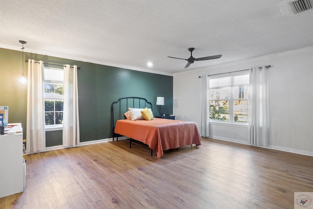 bedroom with ceiling fan, multiple windows, wood-type flooring, and ornamental molding