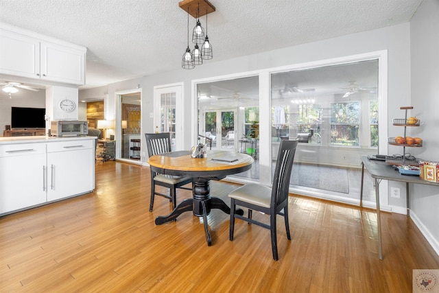 dining space with ceiling fan, a textured ceiling, and light hardwood / wood-style flooring