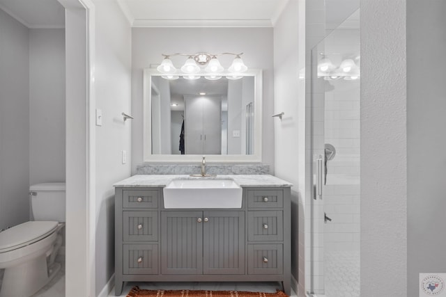 bathroom with vanity, toilet, crown molding, and a shower with shower door