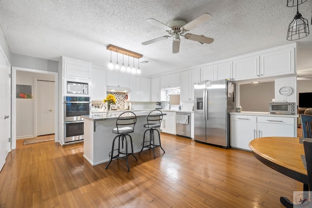 kitchen with white cabinets, tasteful backsplash, hanging light fixtures, and stainless steel appliances