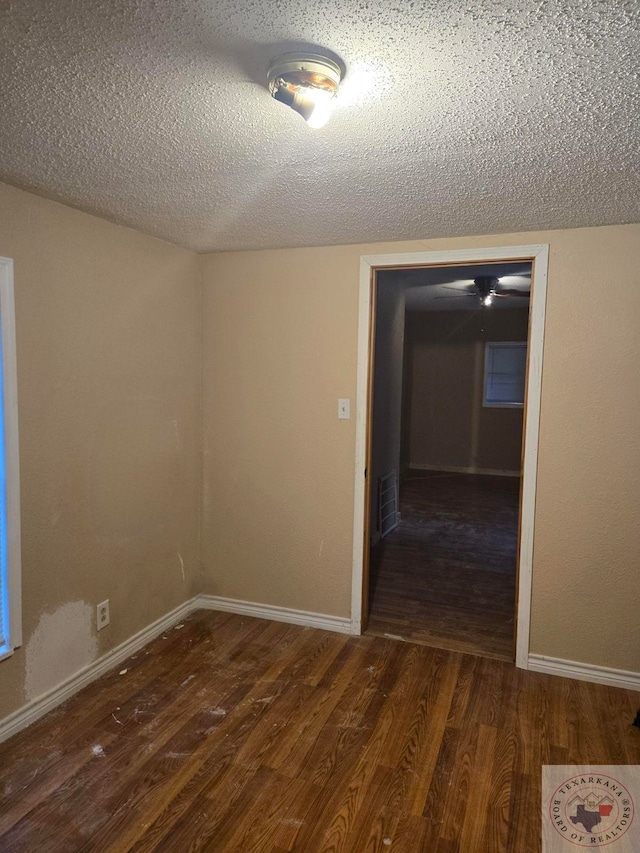 empty room with a textured ceiling and dark hardwood / wood-style flooring