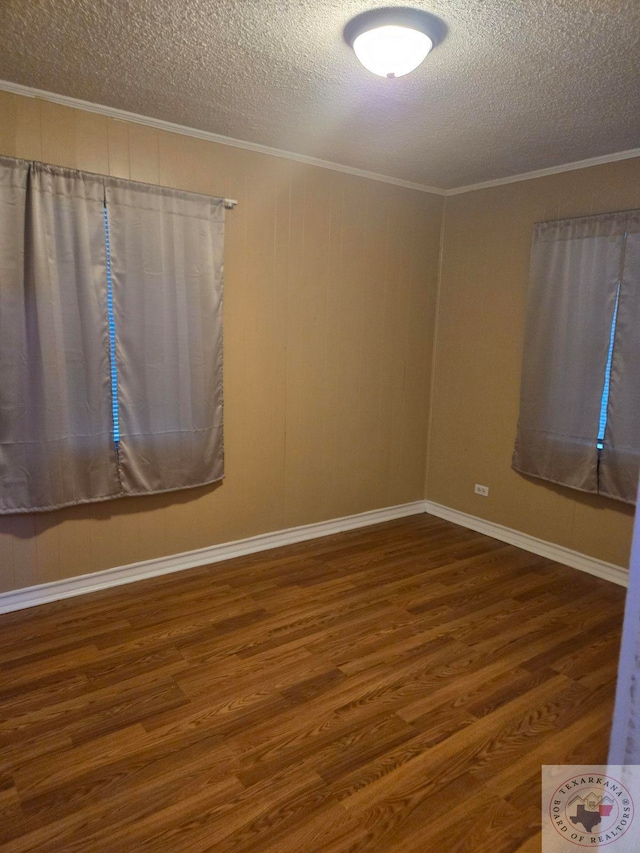 spare room featuring dark wood-type flooring, a textured ceiling, and crown molding