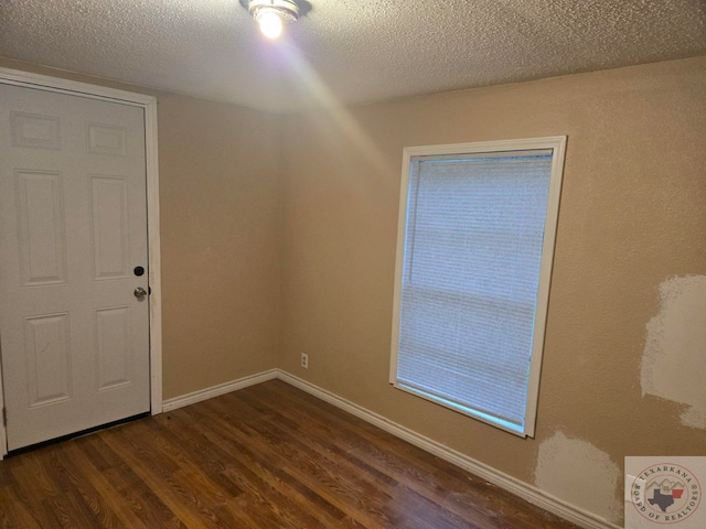 spare room with dark wood-type flooring and a textured ceiling