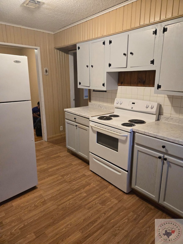 kitchen with white appliances, wooden walls, dark wood-type flooring, and a textured ceiling