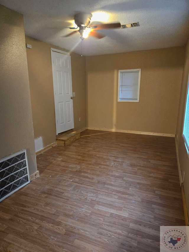 empty room with hardwood / wood-style flooring, a textured ceiling, and ceiling fan