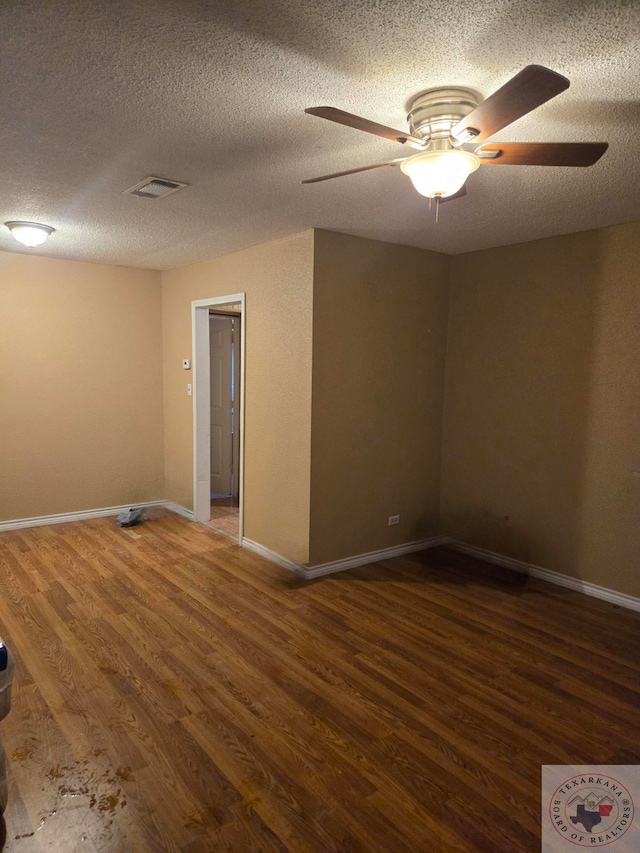 empty room with a textured ceiling, dark hardwood / wood-style floors, and ceiling fan