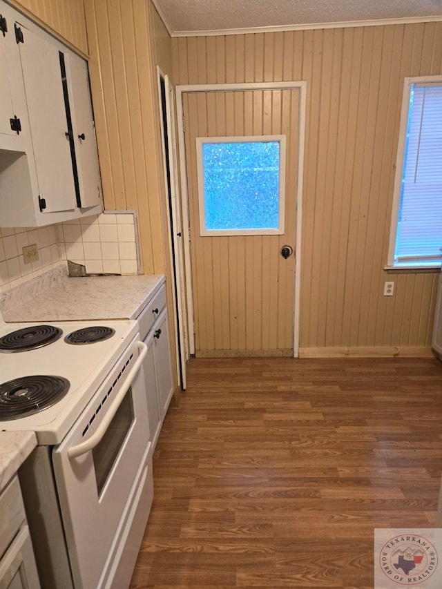 kitchen with white electric range oven, white cabinets, hardwood / wood-style flooring, a textured ceiling, and ornamental molding