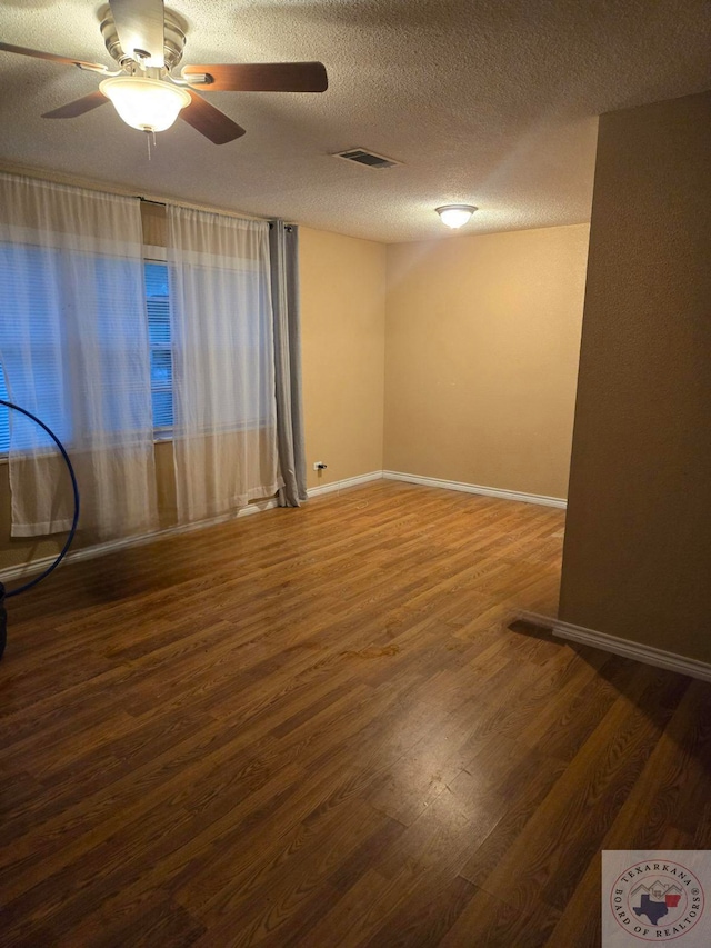 spare room featuring ceiling fan, dark wood-type flooring, and a textured ceiling