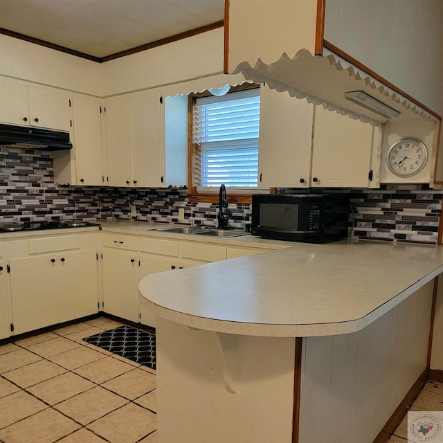 kitchen with sink, black appliances, kitchen peninsula, and white cabinets