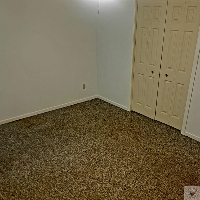 unfurnished bedroom featuring a closet and dark carpet