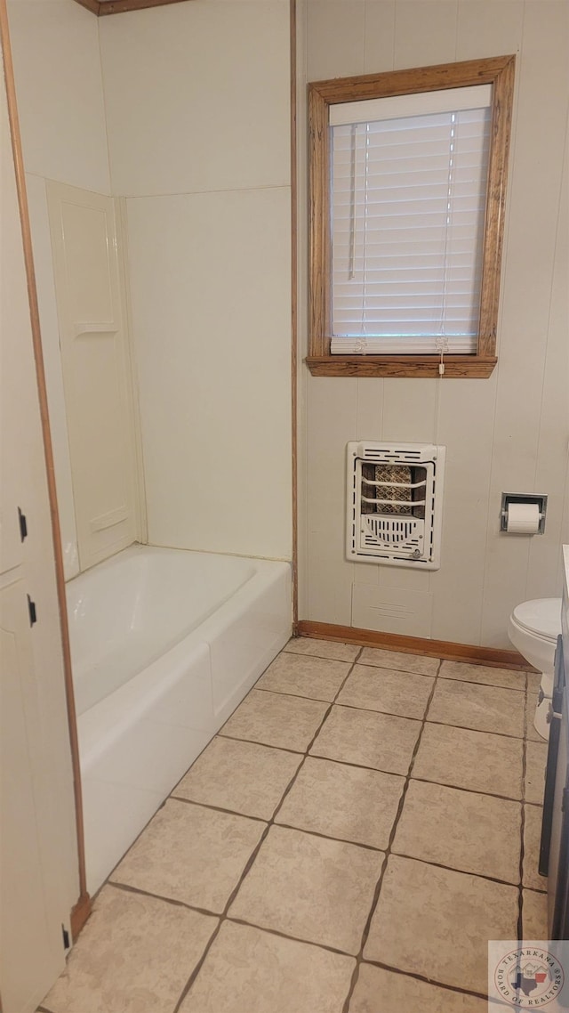 bathroom with toilet, heating unit, a bathing tub, and tile patterned flooring