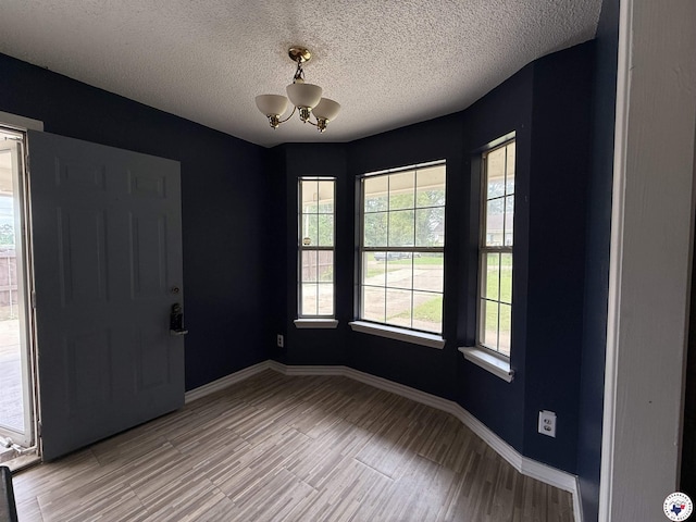 909 Pacific Ave, Wake Village, TX 75501 - spare room with wood finished floors, a chandelier, baseboards, and a textured ceiling