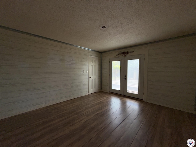 909 Pacific Ave, Wake Village, TX 75501 - unfurnished room with a textured ceiling, french doors, dark wood-style floors, and wooden walls