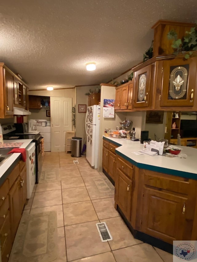 kitchen featuring electric range, white refrigerator, light tile patterned floors, and a textured ceiling