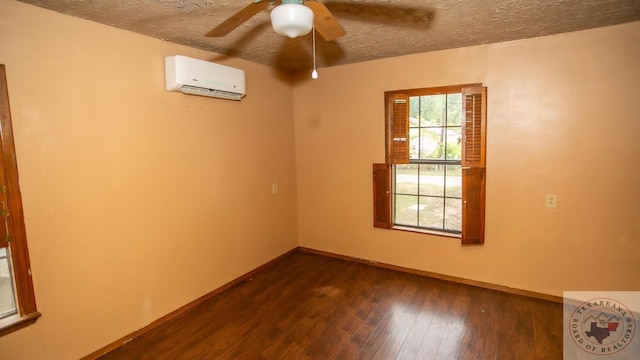 spare room featuring a wealth of natural light, a textured ceiling, dark hardwood / wood-style flooring, and a wall unit AC