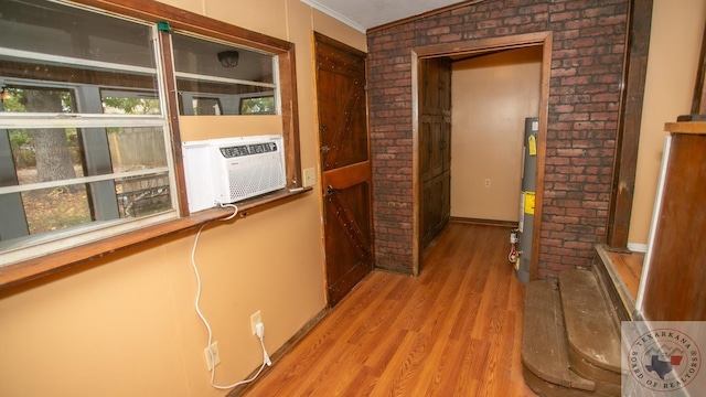 corridor with crown molding, light hardwood / wood-style flooring, vaulted ceiling, water heater, and cooling unit