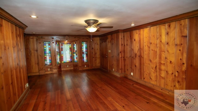 unfurnished room featuring wood walls, dark wood-type flooring, and ceiling fan