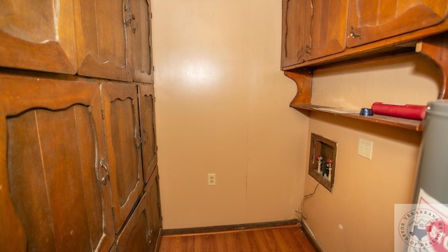 laundry room with hookup for a washing machine, dark hardwood / wood-style flooring, gas water heater, and cabinets