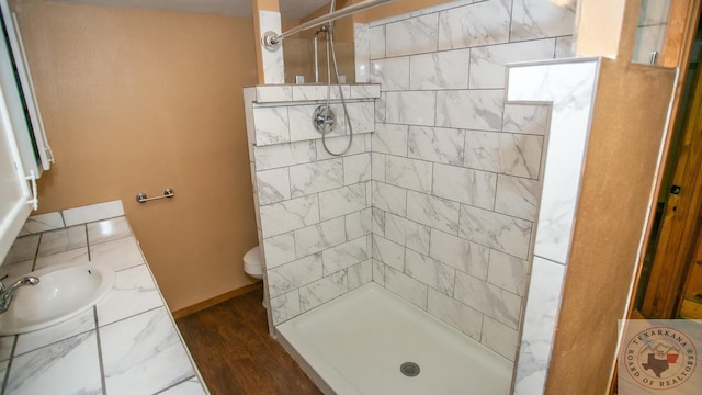 bathroom featuring sink, toilet, a tile shower, and wood-type flooring