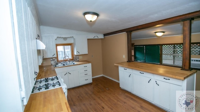 kitchen with vaulted ceiling, sink, white cabinets, butcher block countertops, and gas range gas stove