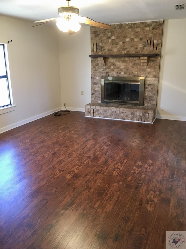 unfurnished living room featuring ceiling fan, dark wood-type flooring, and a fireplace